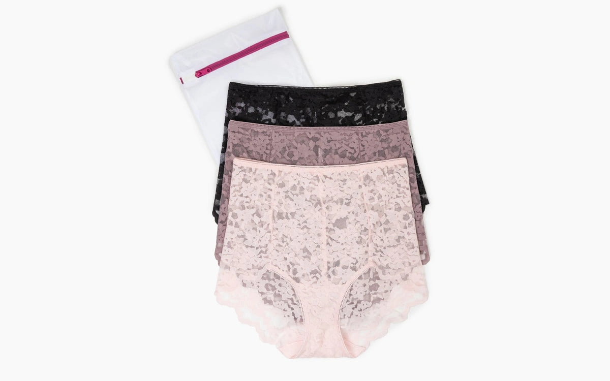 Three lace panties folded beside a mesh laundry bag